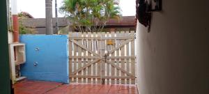 a white fence with a wooden gate in front of a house at Casa Próximo Centro Itanhaém in Itanhaém