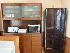 a kitchen with a microwave and a refrigerator at Anan Seaside House in Anan