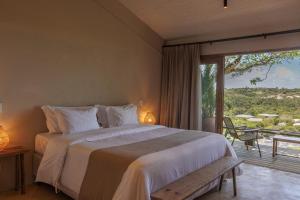 a bedroom with a large bed and a large window at Vila Figo in Trancoso