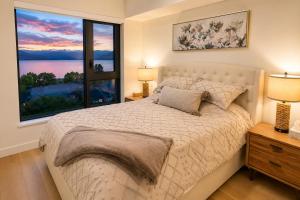 a bedroom with a bed and a large window at Paradise on the Lake in Kelowna +21 photos