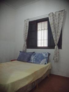 a bedroom with a bed with a window and blue pillows at Casa Próximo Centro Itanhaém in Itanhaém