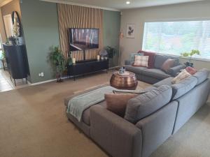 a living room with a couch and a television at Sunset Te Kamo in Whangarei