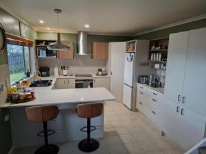 a kitchen with a counter and two bar stools at Sunset Te Kamo in Whangarei