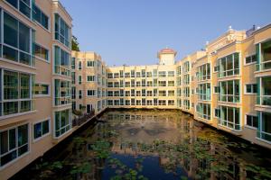 a courtyard of buildings with a pond in the middle at Wellness World Chiva Khao Yai in Ban Wang Sai