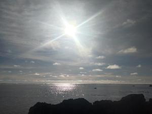 a sun shining in the sky over the ocean at Calicoan Surf Retreat unique family room in Guiuan