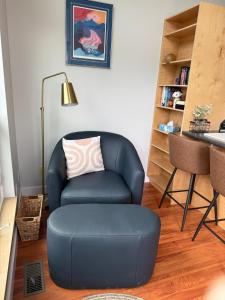 a living room with a blue chair and a ottoman at The Hanson Hideaway in Whitehorse