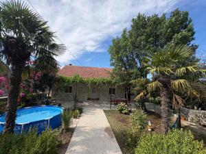 a house with a swimming pool and palm trees at Kuća za odmor in Trebinje
