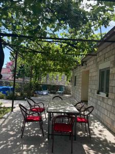 a table and chairs with red cushions sitting under a tree at Kuća za odmor in Trebinje