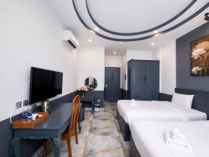 a room with two beds and a desk and a tv at GALANG HOTEL in Ho Chi Minh City