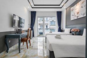 a bedroom with two beds and a desk and a television at GALANG HOTEL in Ho Chi Minh City +50 photos
