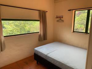a small bedroom with a bed and two windows at Rancho Batatas in Atibaia +53 photos