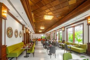 a restaurant with green chairs and tables and windows at ASANA Villas in Siem Reap