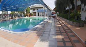 a swimming pool with an umbrella next to a building at Hotel Golf 19 in Ban Hua Khao