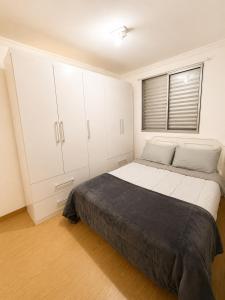 a bedroom with a bed with white cabinets and a window at Apartamento 2 dorms próximo a UFABC e CPTM in Santo André