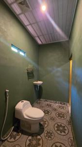 a green bathroom with a toilet and a sink at Bale Sunset Inn in Senaru