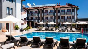 ein Pool mit Liegestühlen und Sonnenschirmen neben einem Hotel in der Unterkunft Mendos Garden Exclusive Hotel Fethiye in Fethiye