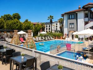 Blick auf den Pool eines Hotels mit Tischen und Stühlen in der Unterkunft Mendos Garden Exclusive Hotel Fethiye in Fethiye
