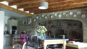 eine Küche mit einer Steinmauer mit einem Tisch und Stühlen in der Unterkunft La ferme de Félix in La Chaze-de-Peyre