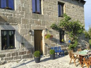 - un bâtiment en pierre avec une table, des chaises et une porte dans l'établissement La ferme de Félix, à La Chaze-de-Peyre