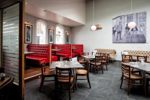 a restaurant with red booths and tables and chairs at ABode Canterbury in Canterbury