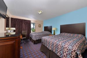 a hotel room with two beds and a desk at Economy Inn Ardmore in Ardmore