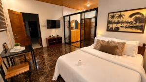 a bedroom with a white bed and a television at Villa Lourdes in Alaminos