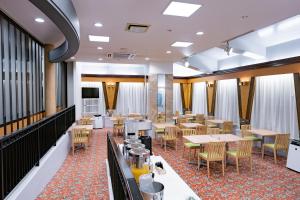 a dining room with tables and chairs and a television at Hotel Route Tsukuba in Tsukuba