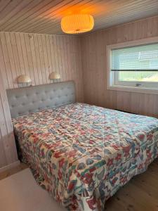 a bedroom with a bed with a comforter and a window at Holiday House On Fanø Near The Sea in Fanø
