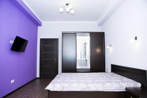 エストサドクにあるLaura Apartmentの紫の壁のベッドルーム1室(大型ベッド1台付)