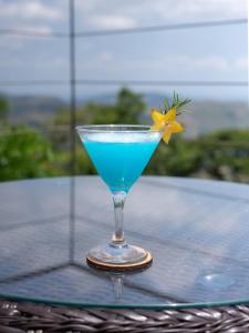 a blue drink in a glass with a yellow flower in it at Villa Cavo - Beneath the Misty Peaks in Haputale
