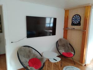 two chairs and a table with a tv on a wall at Garten-Wohnung in Eschen