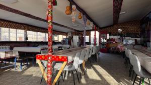 a room with tables and chairs in a restaurant at Besqala Yurt Camp in Kabanbay