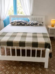 a white bed with a plaid blanket on it at Liz B&B Hideaway in Saint Georgeʼs