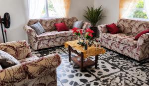 a living room with couches and a table with flowers at Liz B&B Hideaway in Saint Georgeʼs