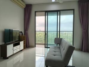 a living room with a couch and a tv and glass windows at Teega Suite - 5 mins from Legoland in Nusajaya