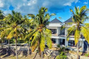 a house with palm trees in front of it at Kelingking Puri Suci Villa in Nusa Penida
