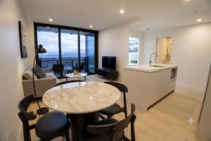 a kitchen and a living room with a table and chairs at OMI Collection Broadbeach in Gold Coast