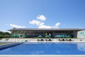 a pool with chairs and umbrellas in front of a building at Nemu Resort Hotel Nemu in Shima