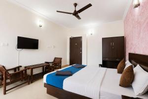 a bedroom with a bed and a desk and a television at Sunlight Stay at Goa in Calangute +10 photos