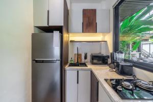 a kitchen with a stainless steel refrigerator next to a window at Sebelas Apartments by EVDEkimi - Modern Stay with Pool near Dining & Shops in Ubud +183 photos