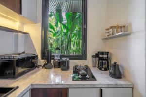 a kitchen with a counter with a microwave and a window at Sebelas Apartments by EVDEkimi - Modern Stay with Pool near Dining & Shops in Ubud