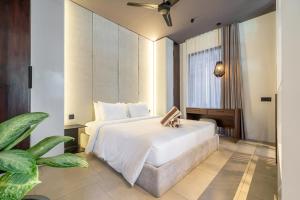 a bedroom with a large white bed and a plant at Sebelas Apartments by EVDEkimi - Modern Stay with Pool near Dining & Shops in Ubud