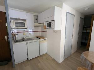 a kitchen with white cabinets and a sink and microwave at Appartement au centre de Barèges in Barèges