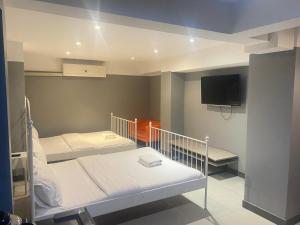 ein Schlafzimmer mit zwei Betten und einem Flachbildfernseher in der Unterkunft Cloud 9 Lodge in Bangkok