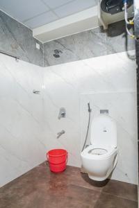 a bathroom with a white toilet and a red bucket at My3 rooms in Vijayawāda +5 photos