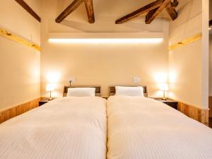two beds in a room with two lamps at 奈良旅館 VILLA East West in Nara