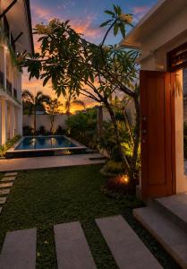 a villa with a swimming pool in front of a house at Braban Sari Guest House Seminyak in Seminyak
