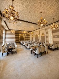 a banquet hall with tables and chairs and chandeliers at The S Crown Somnath in Somnath