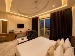 a hotel room with a bed and a large window at The S Crown Somnath in Somnath