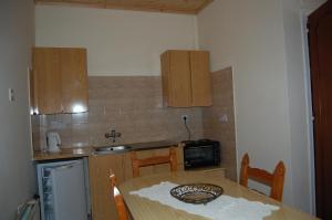 eine Küche mit einem Tisch, einer Spüle und Schränken in der Unterkunft Nicos & Olympia Apartments in Polis Chrysochous